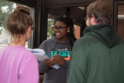 An education major talking to two other students while taking notes